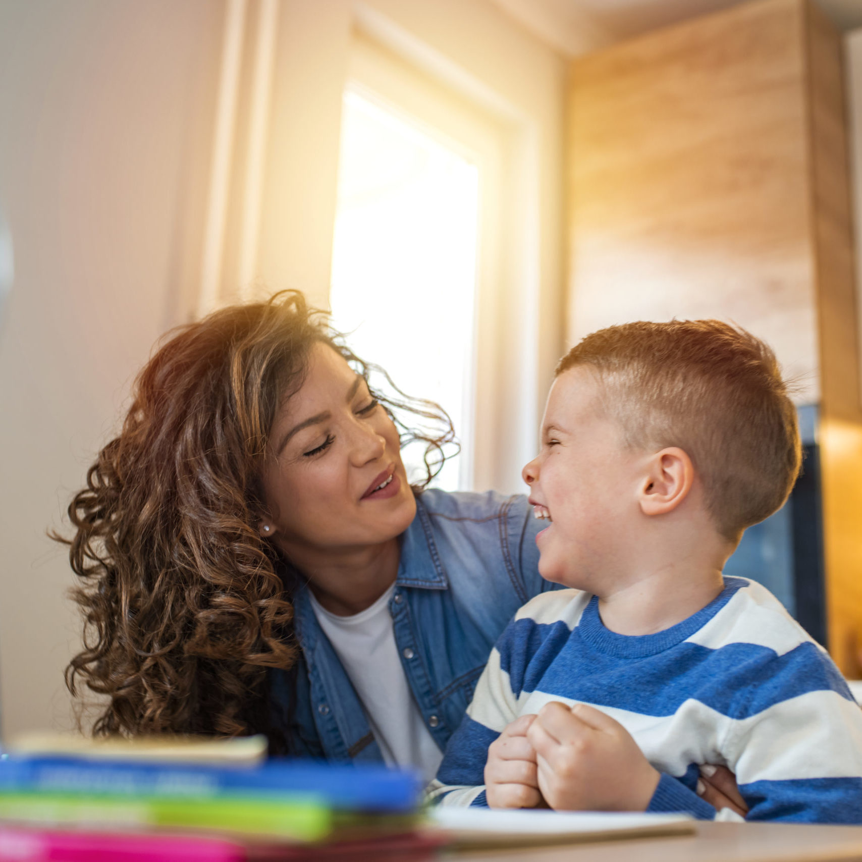 Kind mother helping her son doing homework in kitchen. Mother Helping Son With Homework At Table. Children's creativity. Portrait of smiling mother helping son with homework in kitchen at home